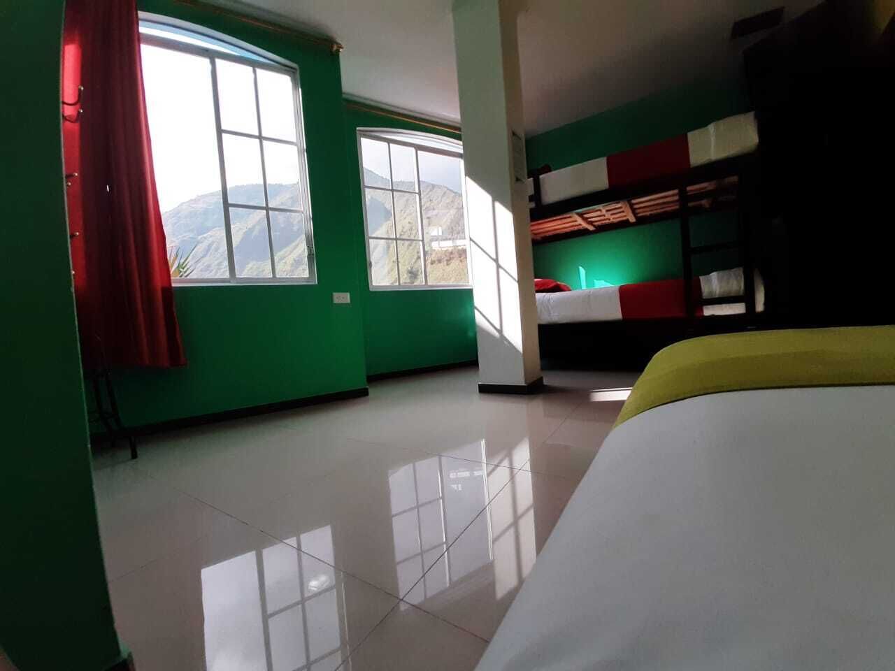 A room with two large windows, a bunk bed, and a bed with a yellow blanket.