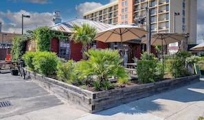 Een restaurant met terras, omringd door groen en een gebouw op de achtergrond.