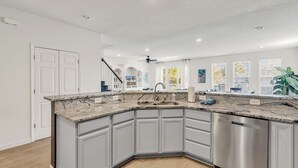 A modern kitchen with a granite countertop, stainless steel appliances, and a view of the outdoors.