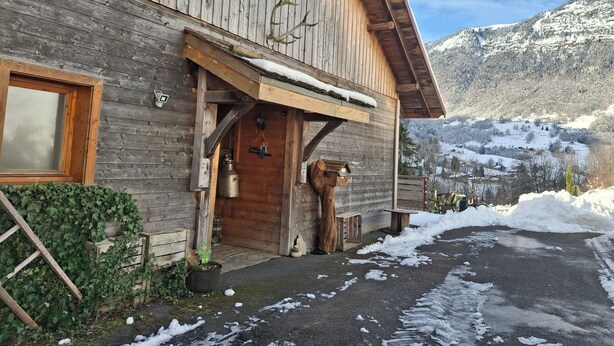 A wooden cabin with a sloped roof, a wooden door, and a window.