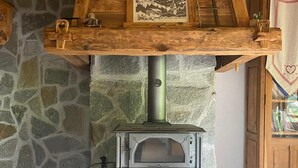 A stone fireplace with a metal stove, wooden beams, and a stone wall.