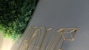 Un mur orné d’une œuvre d’art géométrique en métal formant le mot « HOME », avec un mur végétal vert en arrière-plan.