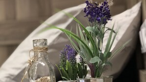 Une table en bois, une bouteille en verre, un pot de fleurs en métal et un récipient en métal contenant des plantes.
