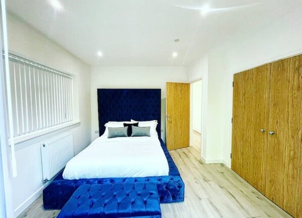 Um quarto com cama, guarda-roupa de madeira e janela com persianas.