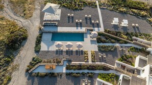 An aerial view of a resort with a swimming pool, sun loungers, and a small outdoor seating area. - Korfi de Milo (Milos)