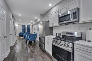 Enjoy cooking in the well-equipped kitchen with stainless steel appliances, white cabinetry, and a tiled backsplash.