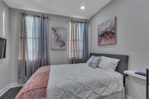 Relax in this serene bedroom with a large bed, white bedding, and a cozy throw blanket.