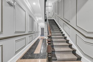 Stunning staircase with a carpeted landing and decorative molding, leading to a spacious interior.