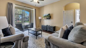 A living room with two sofas, a coffee table, a TV, and a ceiling fan.