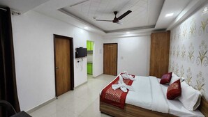 A hotel room with a bed, a TV, and a ceiling fan. - Hotel Abode Inn (New Delhi)