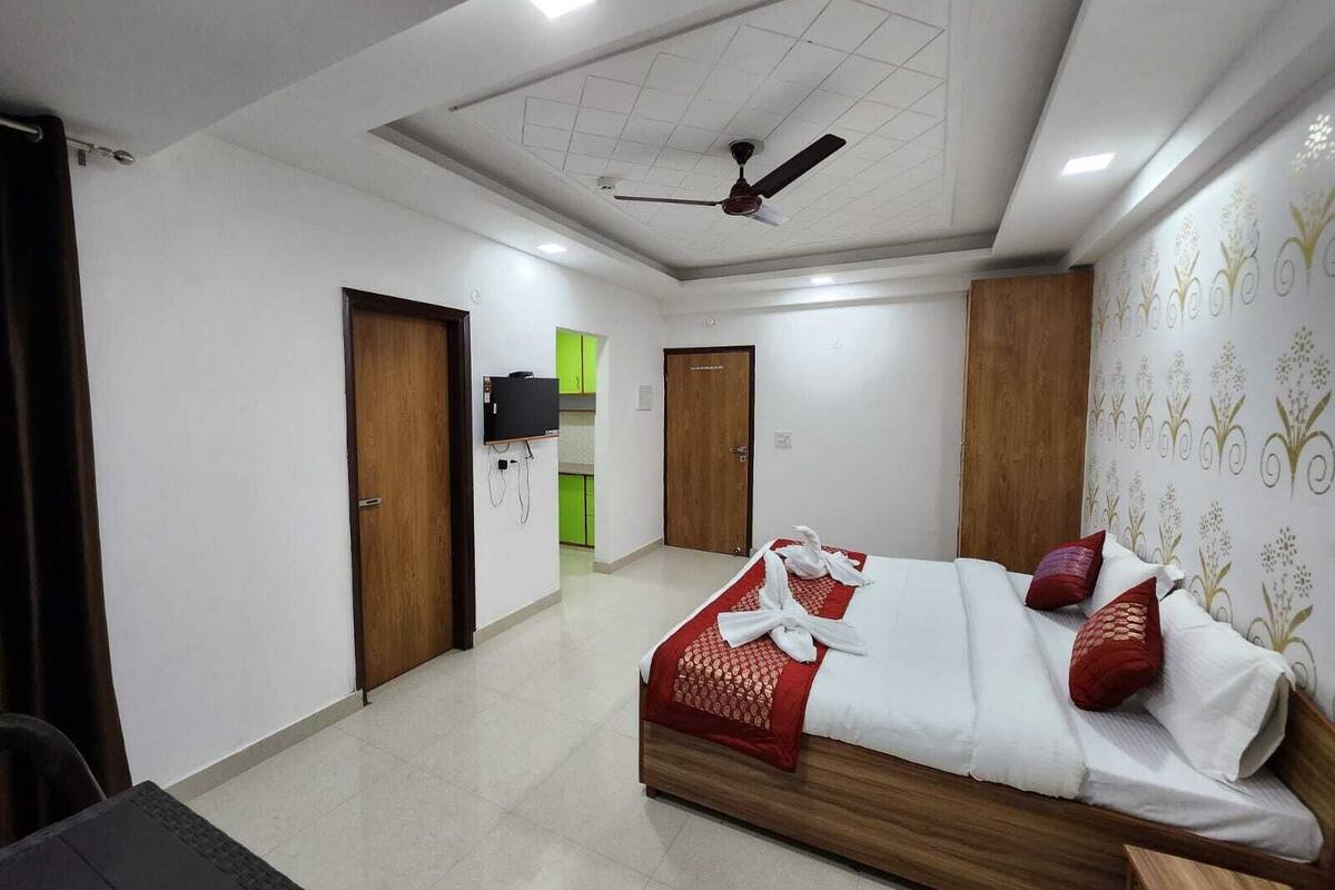 A hotel room with a bed, a TV, and a ceiling fan.