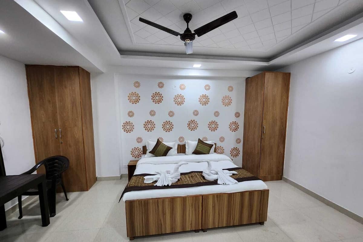 A bedroom with a bed, wooden wardrobe, ceiling fan, and a patterned wall.