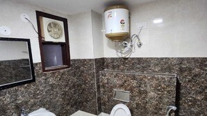 A bathroom with a sink, toilet, and a wall-mounted heater. - Hotel Abode Inn (New Delhi)