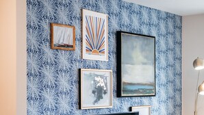 Un salon moderne doté d’un grand téléviseur à écran plat, d’un meuble de rangement en bois et d’un mur orné d’un motif décoratif.