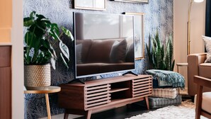 Un salon moderne doté d’un grand téléviseur à écran plat, d’un meuble de rangement en bois et d’un papier peint à motifs.