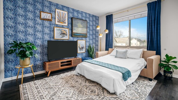 Une chambre moderne avec un grand lit, un téléviseur posé sur un meuble en bois et une vue sur la ville par la fenêtre.