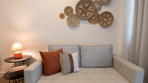 A modern living room with a light grey sofa, two pillows, a small round table with a lamp, and decorative wall art. - 4 Minutes From Ipanema Beach Fa202 (Rio de Janeiro)