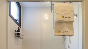 A shower with a glass door, a towel rack with two towels, and a small shelf with a bottle. - 4 Minutes From Ipanema Beach Fa202 (Rio de Janeiro)