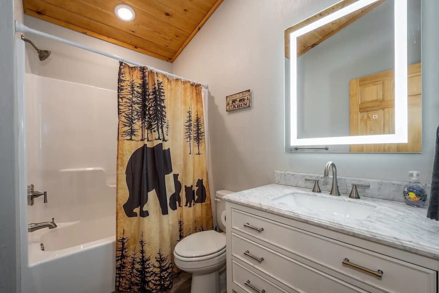 A bathroom with a bathtub, toilet, and a vanity with a mirror.