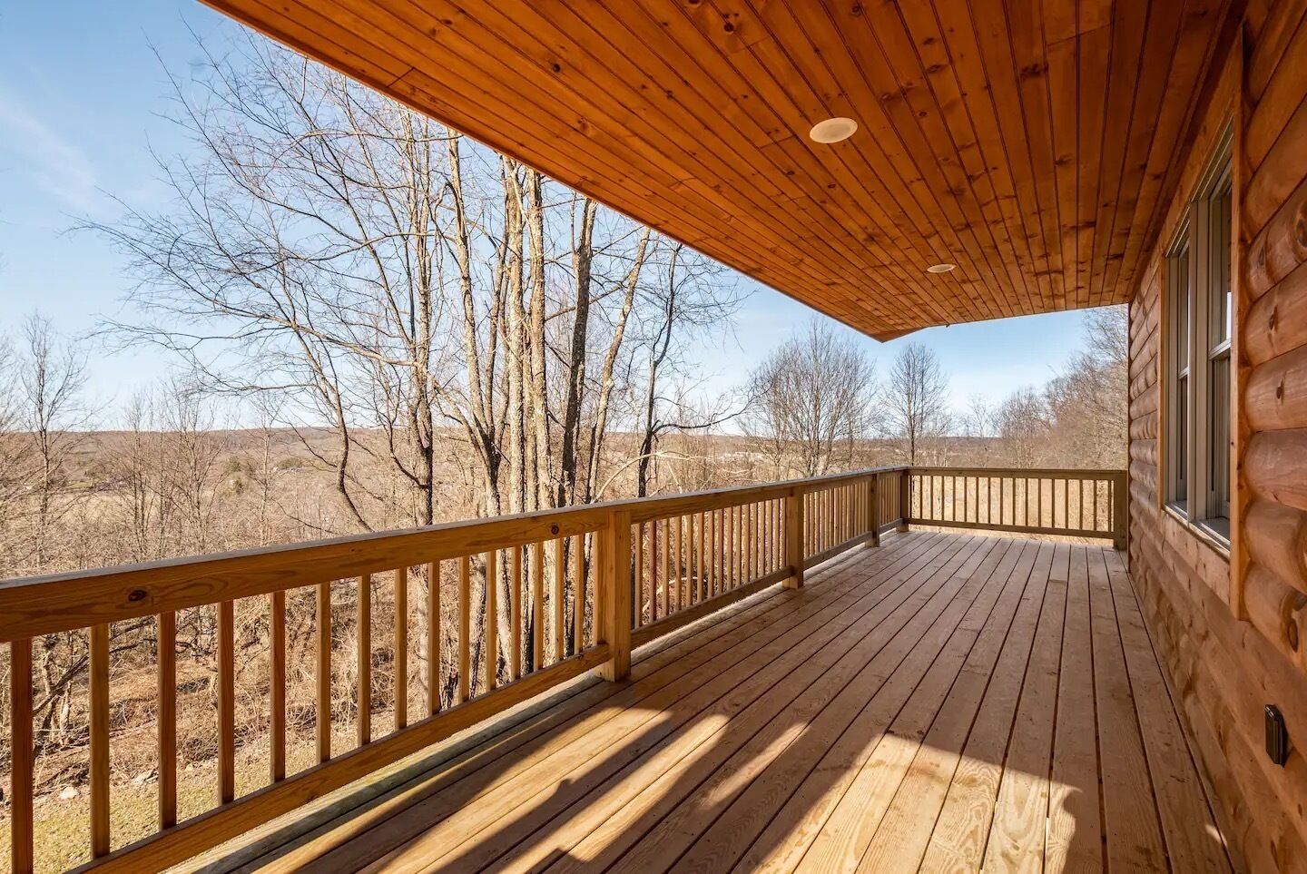 Una terraza de madera con barandilla, con vistas a un paisaje árido con árboles.