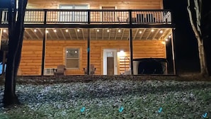 A two-story log cabin with a balcony, a door, and a small porch area.