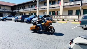 A parking lot with several vehicles, including a motorcycle with a sidecar. - Alpine Valley Inn (Helen)