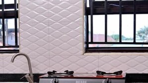 Una cocina con estufa a gas, armarios de madera y ventana con vista a edificios.