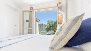 A bedroom with a bed, a view of a mountainous landscape, and a window with curtains. - Villa with beautiful sea view (Tertenia)