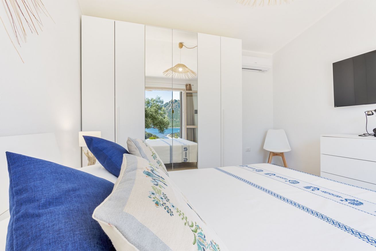 Una camera da letto moderna con un letto grande, un armadio, una TV e vista sull'esterno.