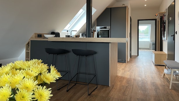 A modern kitchen with a central island, bar stools, and a skylight.