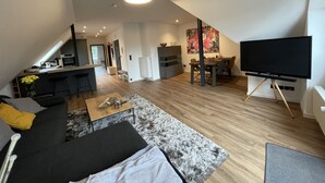 A modern living space with a kitchen, dining area, and a large flat-screen TV.