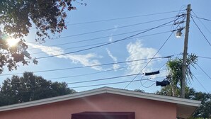 A small house with a red awning, a white door, and two potted plants. - Escape By The Bay (Tampa)