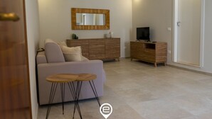 Ein modernes Wohnzimmer mit einer Couch, einem Couchtisch, einem Fernseher und einem Holzkasten.