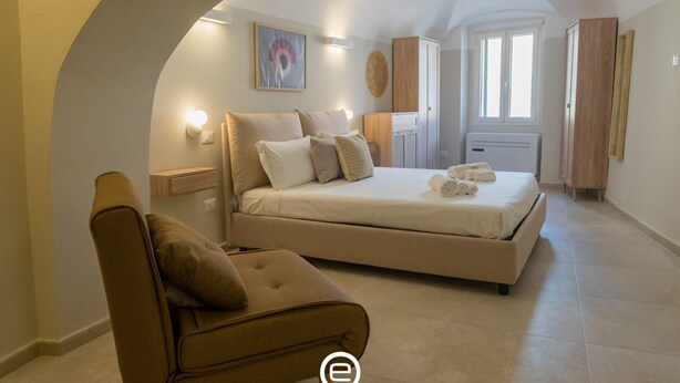 Ein Schlafzimmer mit Bett, Stuhl, Kleiderschrank und Fenster.
