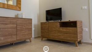 Ein modernes Badezimmer mit einem Holzbadezimmermöbel, einem Spiegel und einem Fernseher.