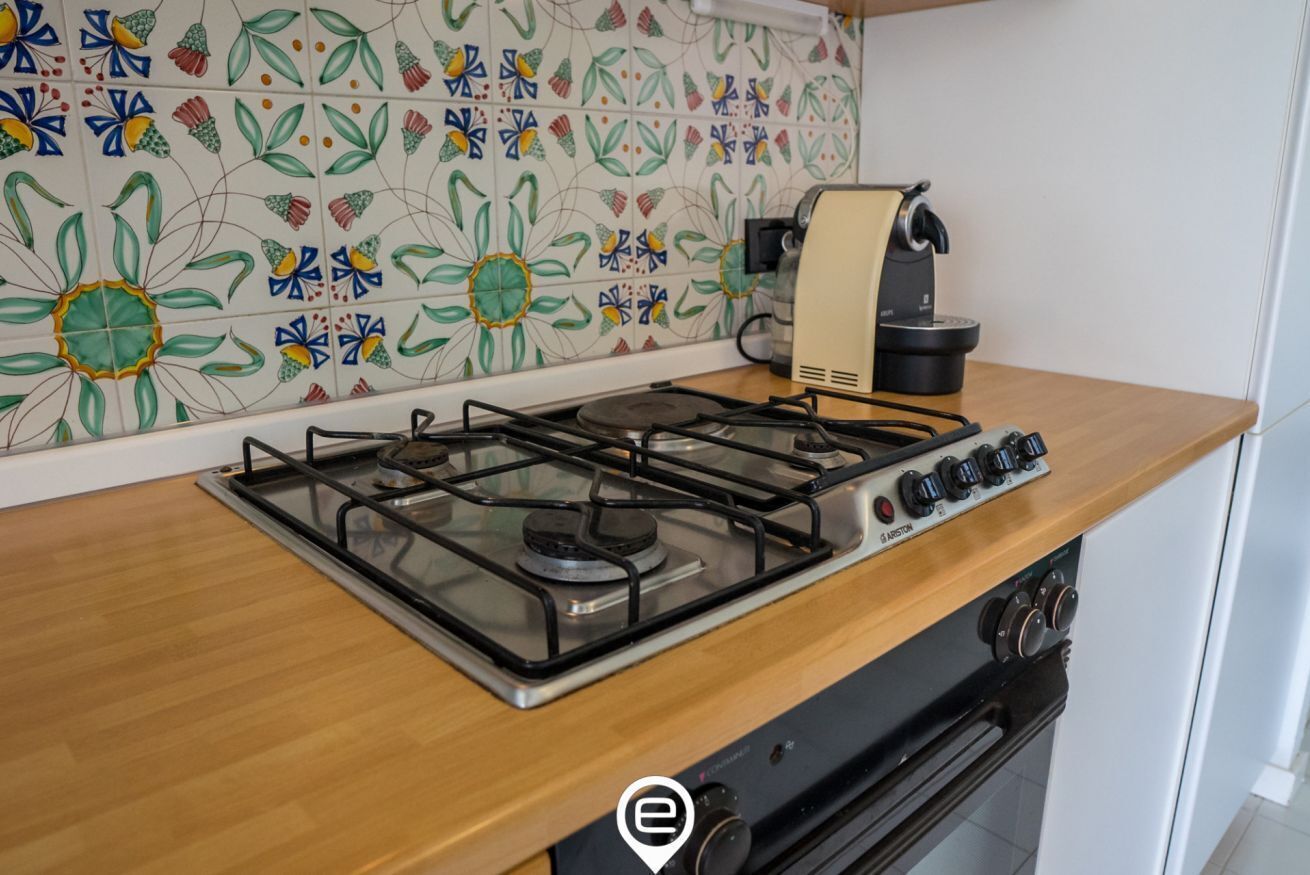 A kitchen with a gas stove, a coffee maker, and a tiled backsplash.