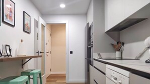 Une cuisine étroite avec un plan de travail en bois, un lave-vaisselle et une porte donnant sur une autre pièce.