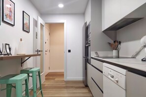 A narrow kitchen with a wooden countertop, a dishwasher, and a door leading to another room.