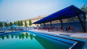 Una piscina con zona relax coperta e sedie rosse.