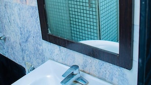 Un bagno con un lavandino bianco, uno specchio con cornice in legno scuro e una parete rivestita di piastrelle.