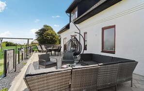 A patio with wicker furniture, a hanging chair, and a table. - Stunning home in Farsø with WiFi (Farsø)