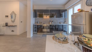 A modern kitchen with a central island, built-in appliances, and a dining area with a table set for four. - ANNIE HOUSE - Chic and Comfortable Apartment (Sestri Levante)