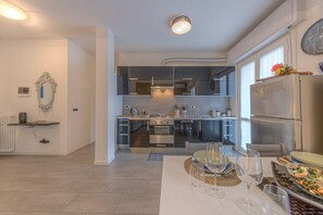 Une cuisine moderne dotée d’un îlot central, d’appareils électroménagers intégrés et d’un coin repas avec une table dressée pour quatre personnes.