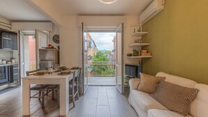 A modern kitchen with a dining table, a sofa with patterned cushions, and a view through an open door to a balcony. - ANNIE HOUSE - Chic and Comfortable Apartment (Sestri Levante)