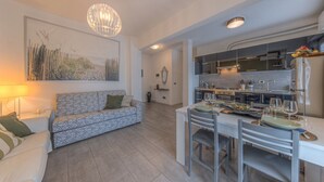 A modern living room with a sofa, dining table, and kitchen area. - ANNIE HOUSE - Chic and Comfortable Apartment (Sestri Levante)