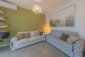 Un salon avec deux canapés, un téléviseur, une lampe et un tableau encadré au mur.