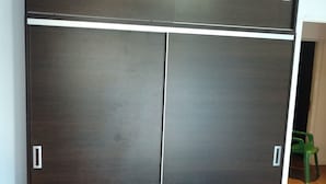 A dark-colored wardrobe with two doors and a handle on each door. - Casa Colinas 2 (Mar del Plata)