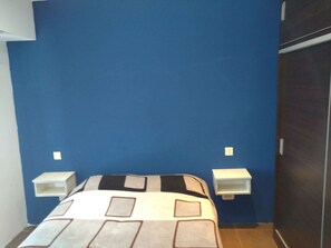 A bedroom with a bed, blue walls, and two bedside tables.