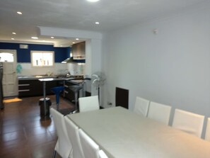 A modern kitchen with white cabinets, a blue countertop, and a dining area with a white table and chairs.