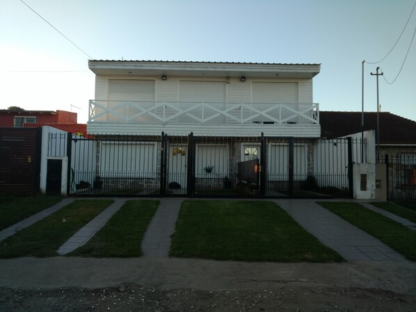 A large, single-story building with a white facade and a black metal fence.